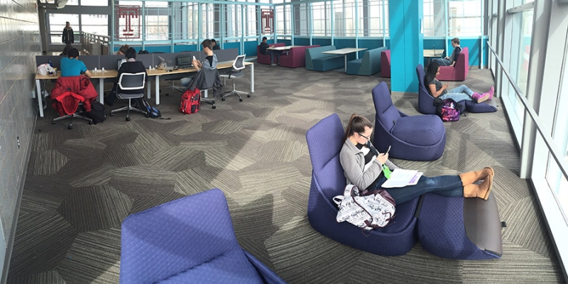 A female student sitting in a blue chair in the refurbished Owls Nest.