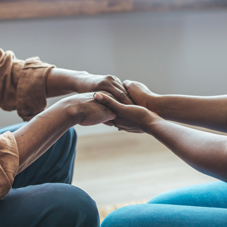 Personal care ome employee clasping hands with patient.