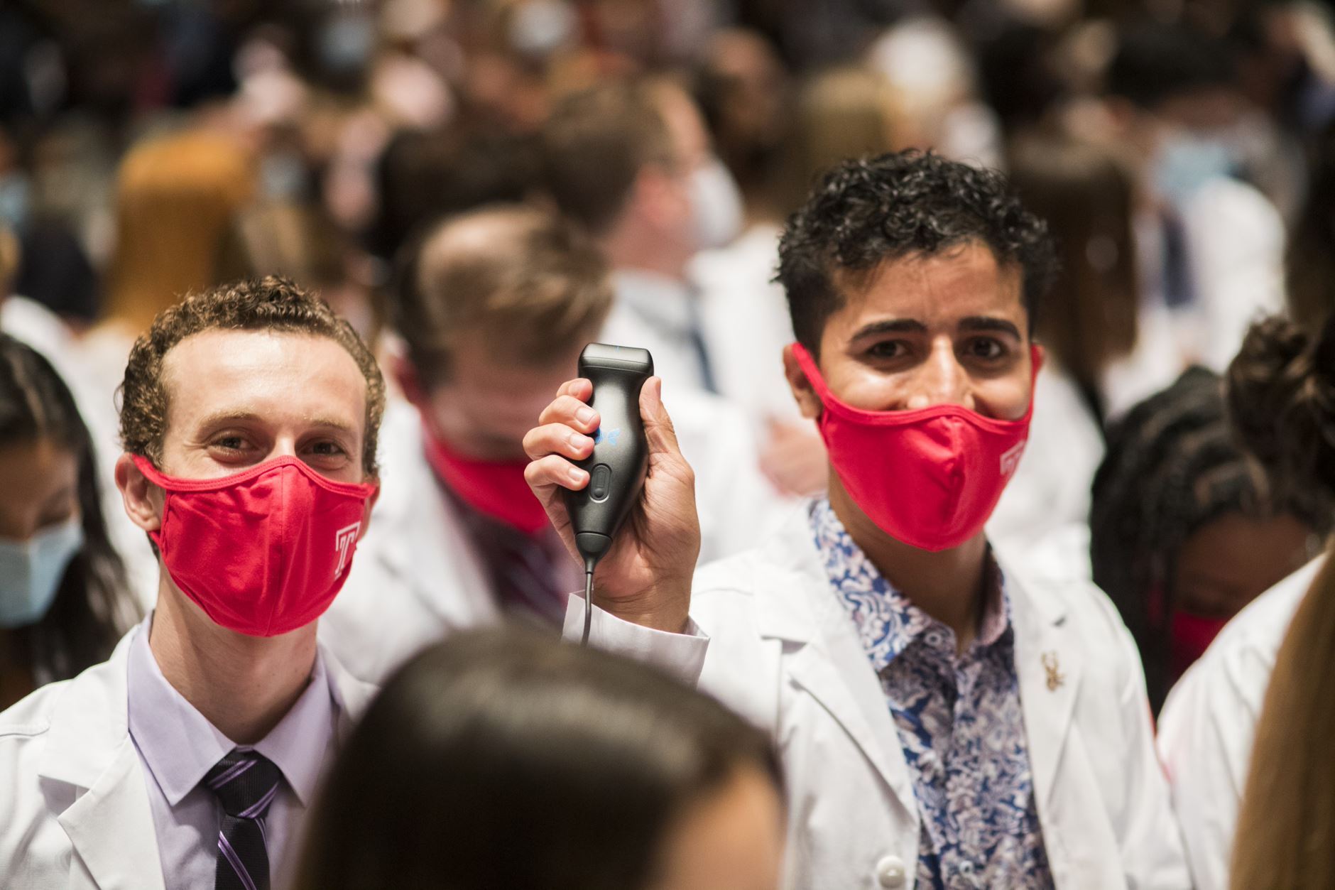 A student displays their new ultrasound device at a white coat ceremony.
