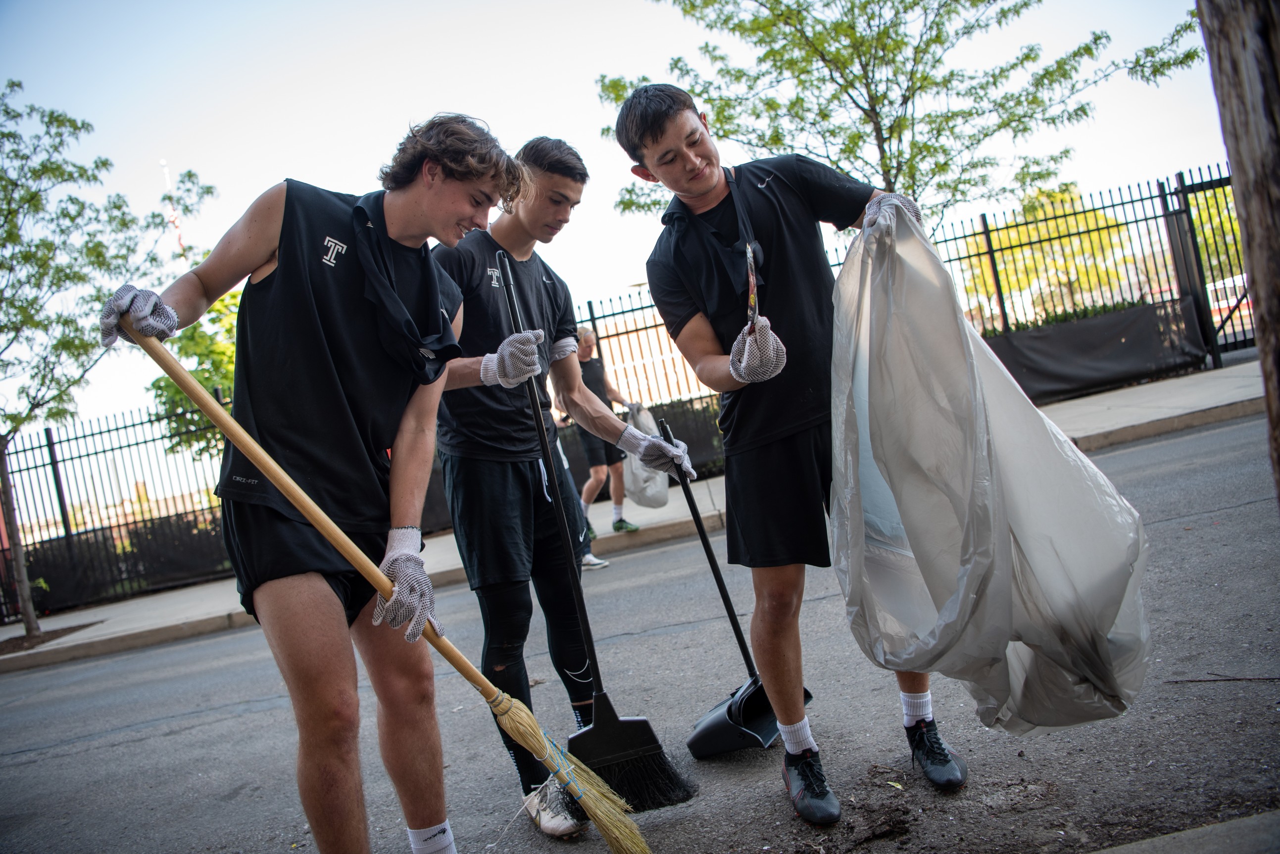 Image of men's soccer players cleaning up the area near Temple Sports Complex.