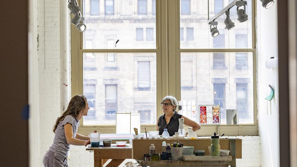 Tyler School of Art and Architecture Dean Susan Cahan speaks with Madison Tubbs, TYL ’26, a post-MFA fellow in the artist’s studio inside the Pennsylvania Academy of the Fine Arts’ historic building.