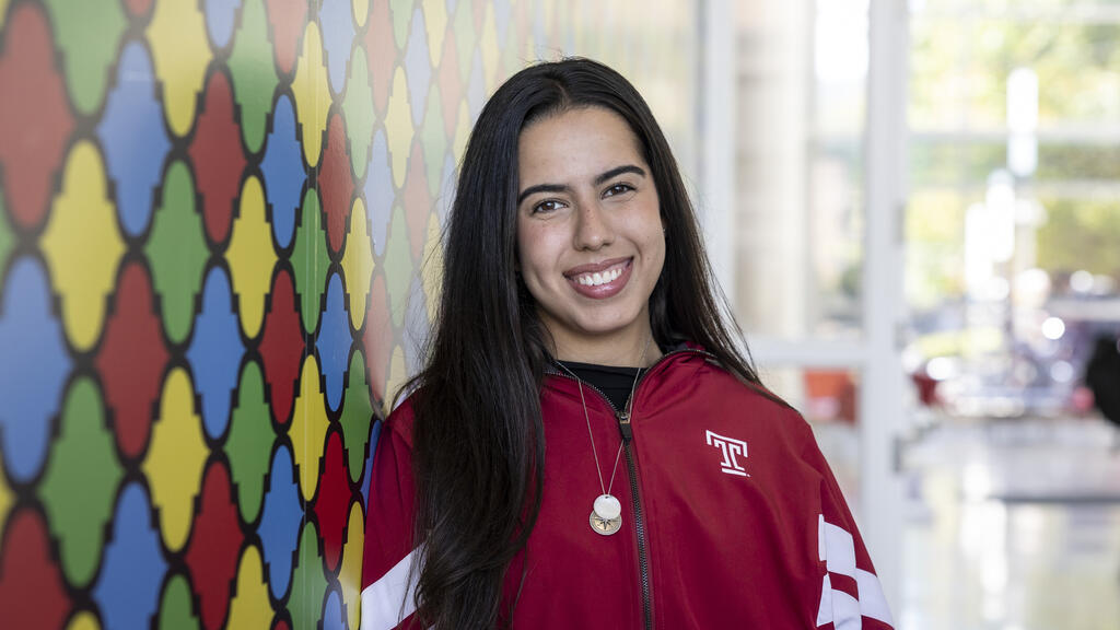 Raphaela leans against a colorful wall in the Art of Bread inside Tyler School of Art