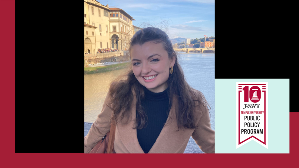 image of Christina in a tan coat standing in front of a river smiling at the camera