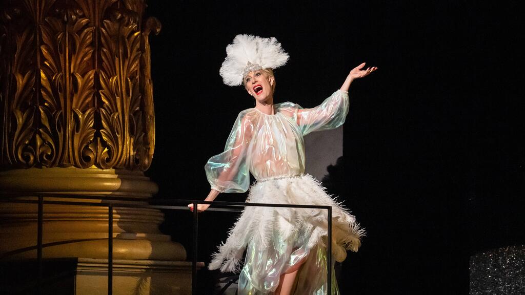 Photo of singer in white costume on stage performing