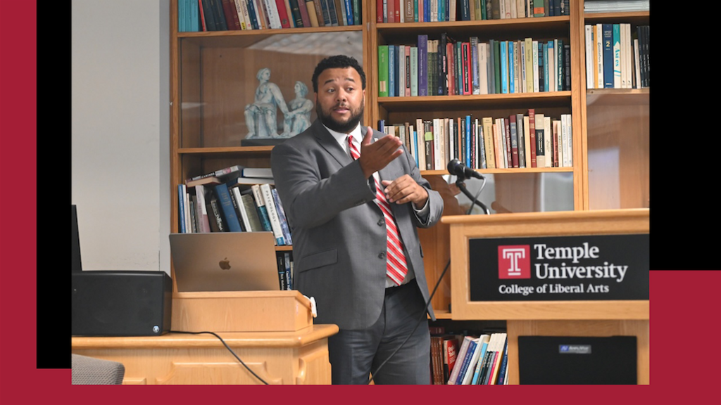image of Nyron in a grey suit presenting to the crowd at the podium