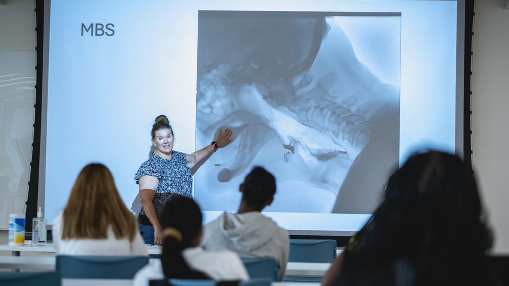 A guest speaker in the pre-college institute introduces students to the work of a medical speech-language pathologist.