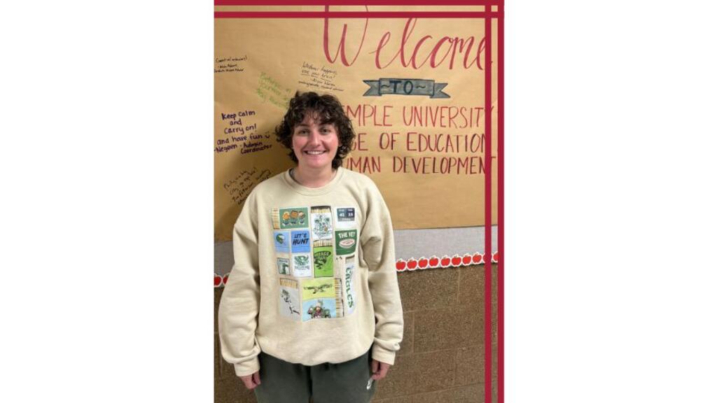 A student stands in front of a welcoming decorative bulletin board