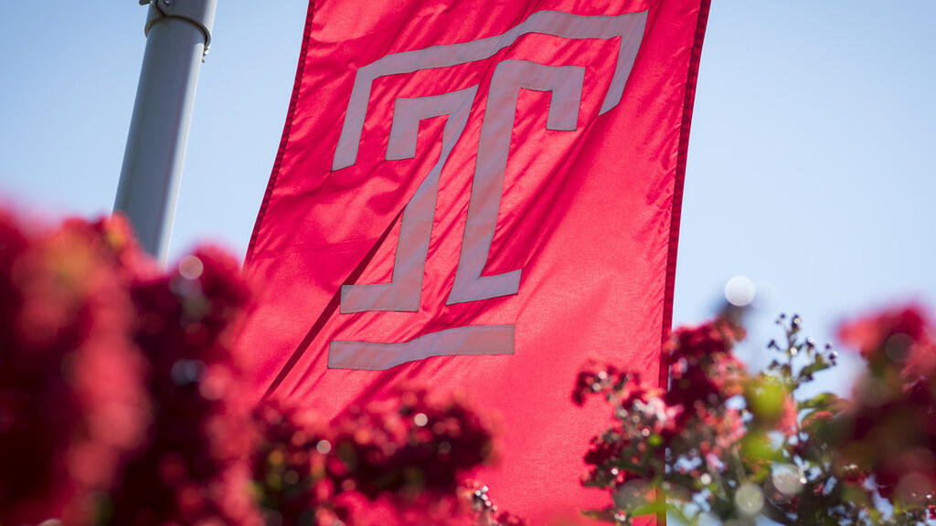 A photo of the Temple flag with flowers.