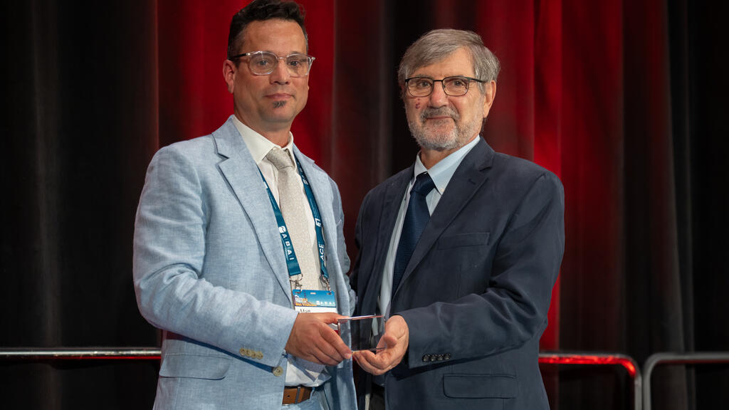 Matt Tincani stands on stage with ABAI President Mark Galizio