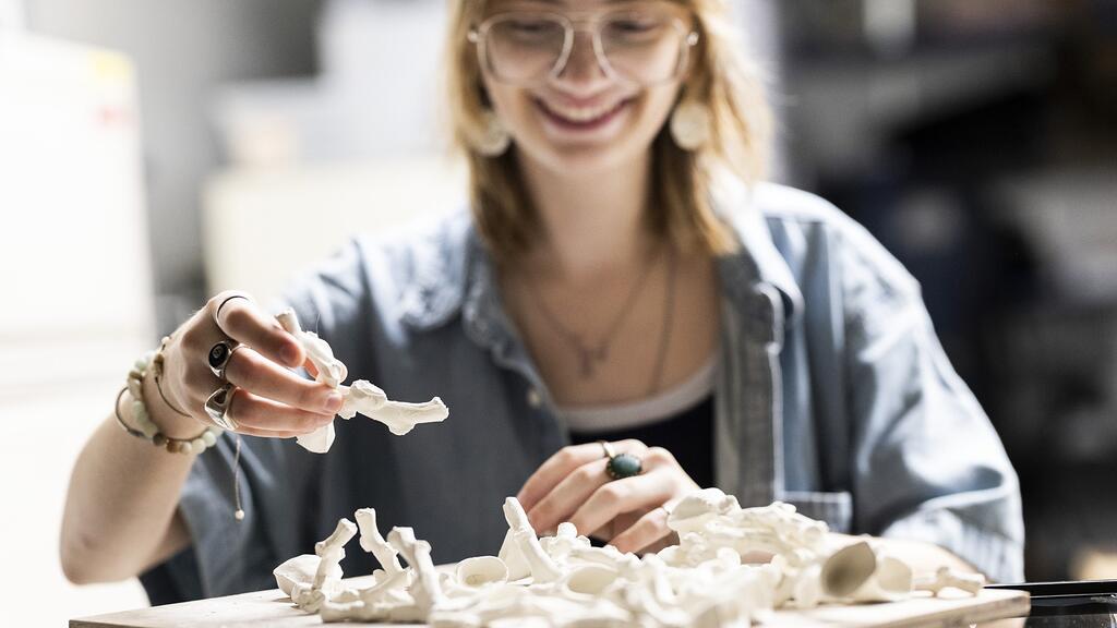 Inside the Cordes Laboratory, Eva Close, Class of 2027, looks through her self-made porcelain corals, which she created through Temple’s Diamond Research Scholars Program.