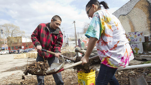 Two volunteers shoveling dirt into buckets.