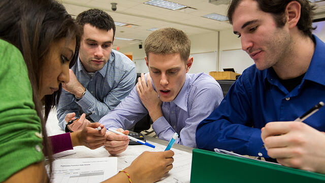 Four students around a table working on an assignment.