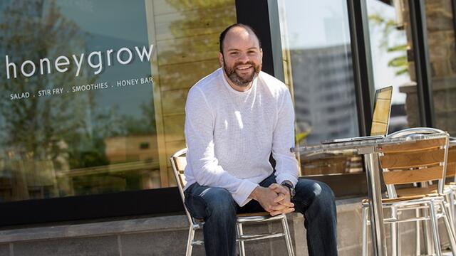 Justin Rosenberg sitting at a table outside of a honeygrow location.