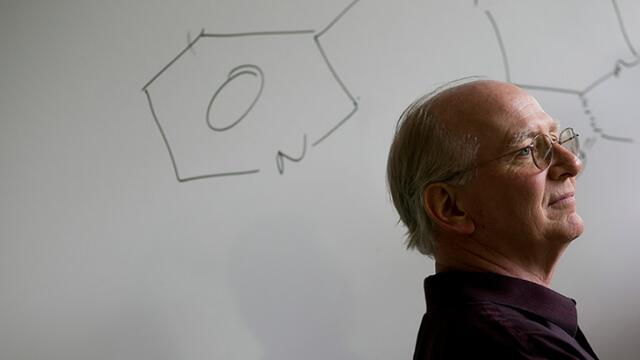 Jim Guare standing in front of a drawing of a chemical compound.
