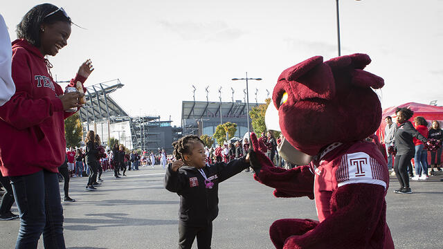 A little girl giving Hooter a high five at a tailgate outside Lincoln Financial Field.