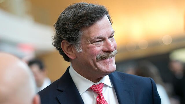 Larry Kaiser smiling as he mingles with guests at medical school event.