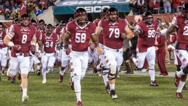 Temple football players running onto field for a game
