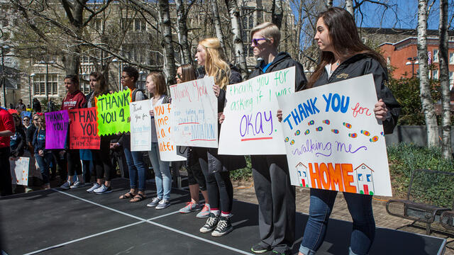 Students holding signs during a walk to raise awareness around sexual assault.