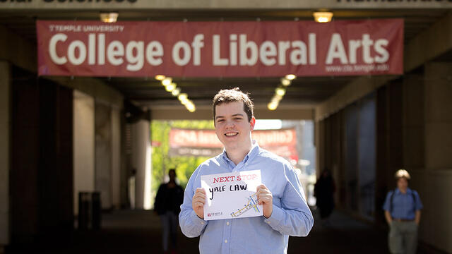man in a blue shirt standing between two buildings on Temple s Main Campus.