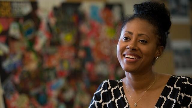 A woman wearing a black and white dress and smiling.
