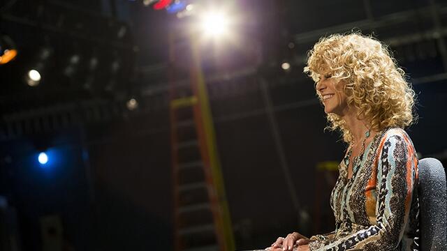 Sharon Pinkenson smiling as she sits on a stage.