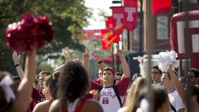 A group of students wearing Temple gear on campus.