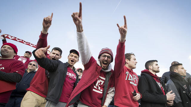 A group of students cheering at a Temple football game.