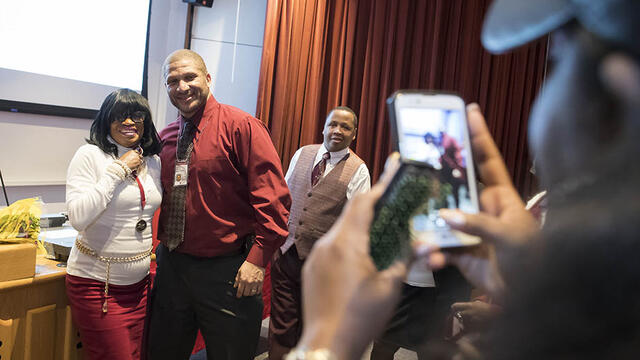 A student and an administrator getting their picture taken with a cell phone.