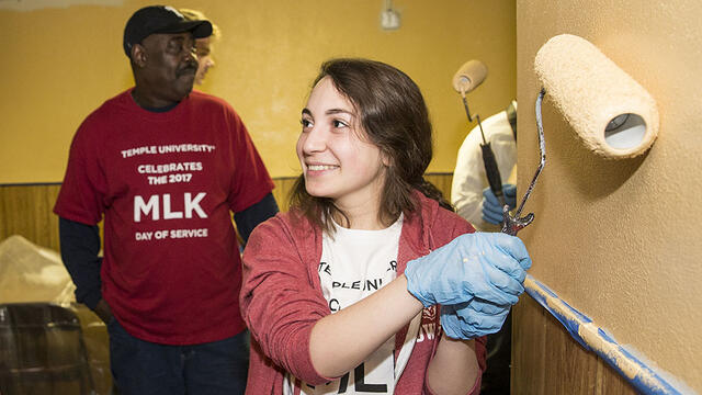 A student painting a wall as part of a service project.