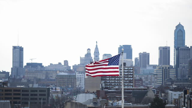 The US flag flying against the Philadelphia skyline.