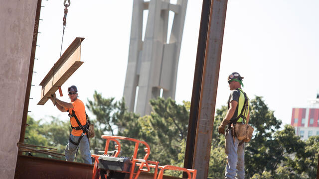 Construction workers place steel beams on Temple s new library.