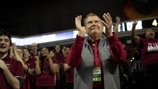 President Richard M. Englert clapping in the stands among Temple students at a basketball game.