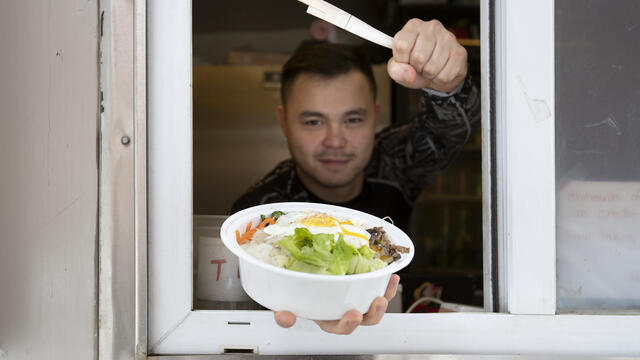A food truck vendor shows off a meal