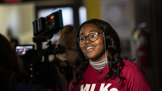 Image of a Black woman wearing a cherry and white MLK Day shirt.
