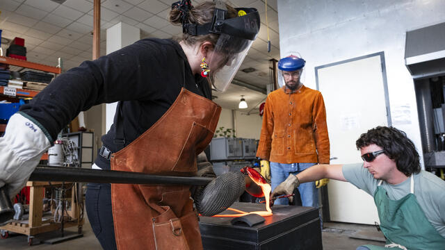 Image of Jessica Jane Julius and two helpers working with molten glass.