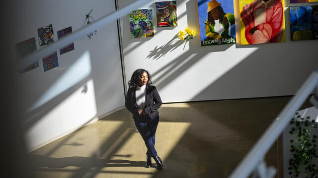 Image of Taylor Sanders standing in front of various paintings.