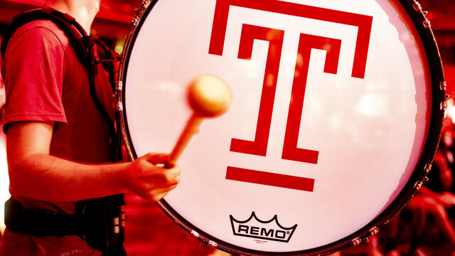 Student playing a drum with a T on it