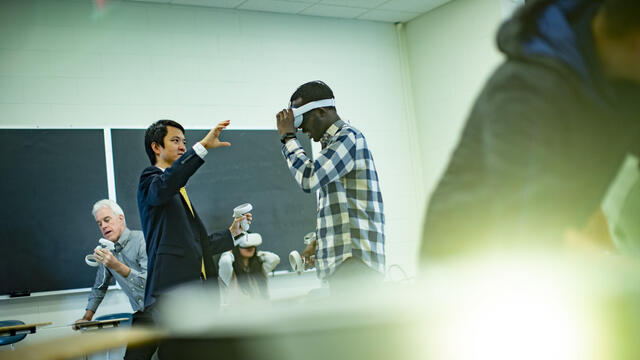 mage of Di Liu demonstrating virtual reality technology with teachers and students in a classroom.