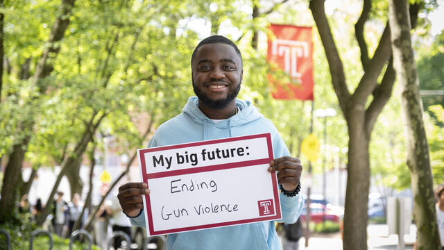 Andrew Ankamah holding a sign that says ending gun violence.