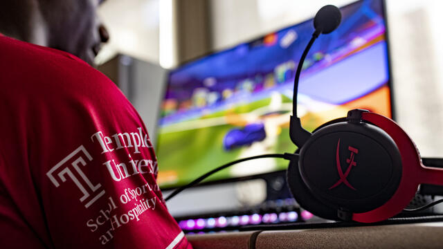 Image of a student wearing a Temple esports jersey playing a PC game.