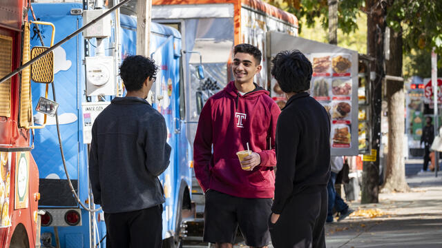 Students standing and talking near food trucks on Main Campus