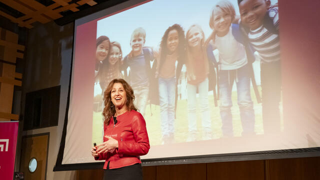 Sherri Hope Culver in front of a screen displaying children