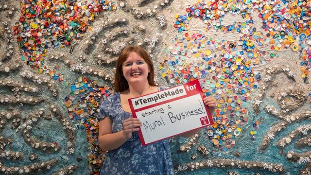 Abigail McNavage holding a #TempleMade sign in front of her painting