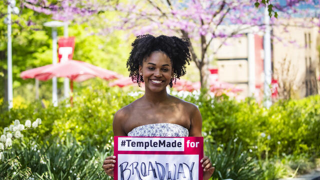 Jasmine Villaroel holding a Temple Made for sign outside on Main Campus