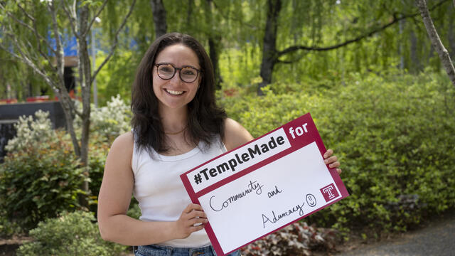 Trista Mayo standing outside holding up a Temple Made for sign