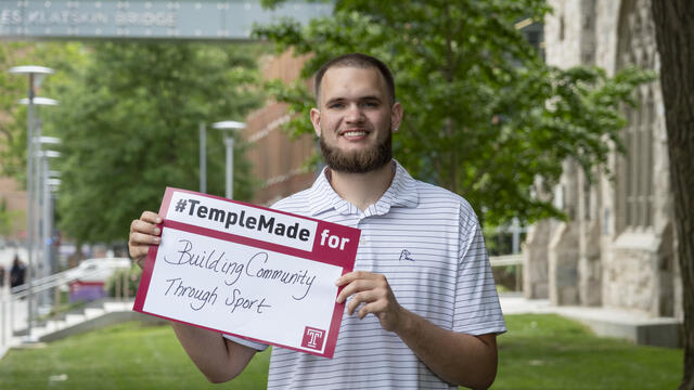 Ezekiel Cartwright standing outside holding up a Temple Made for sign
