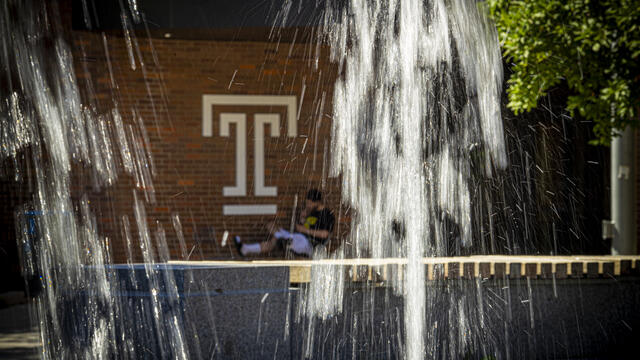 A student is pictured behind a fountain.
