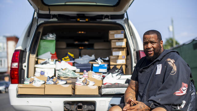 Image of a North Philadelphia resident in front of his truck load of sneakers.