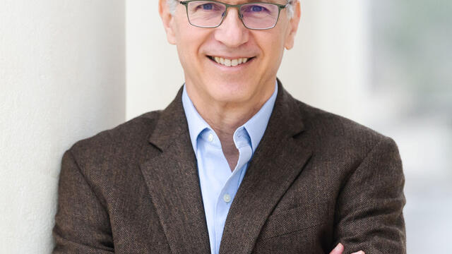 image of Marc Selvestone, wearing glasses, wearing a blue button down shirt and dark grey blazer