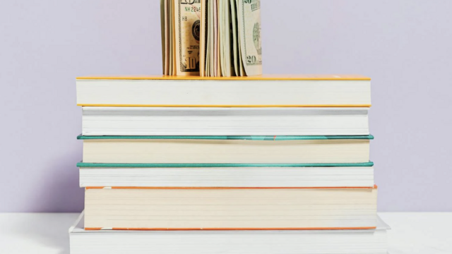 A stack of books with a group of paper currency propped up on top